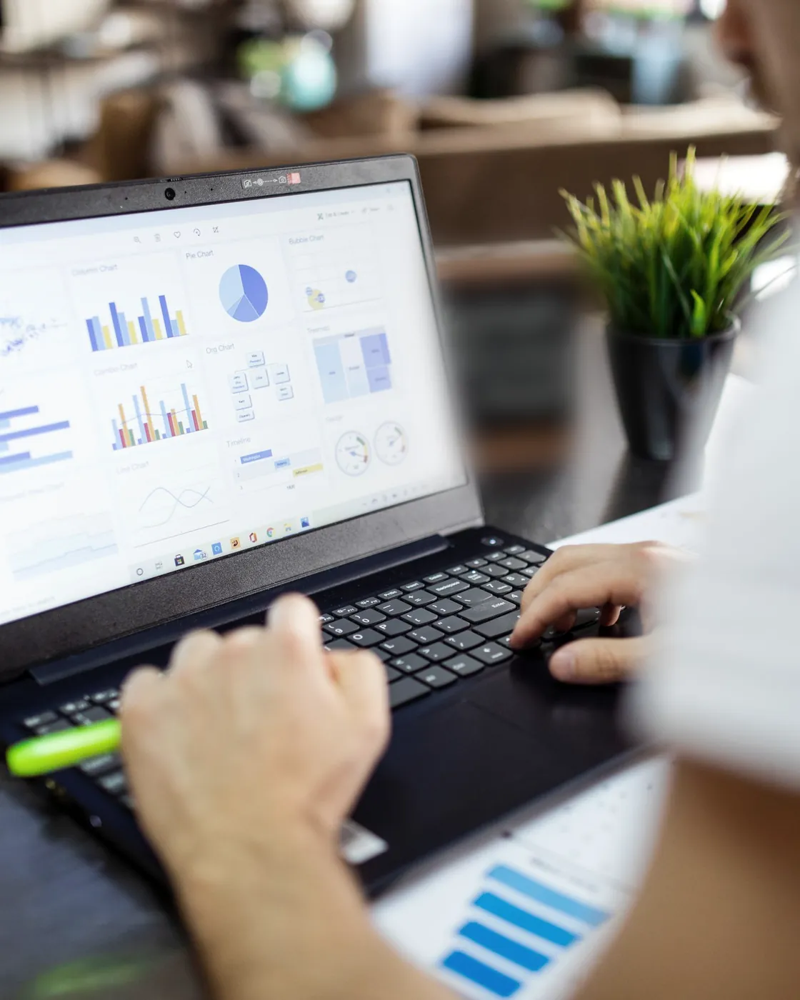 Mãos digitam num notebook que mostra um painel de gráficos de gestão